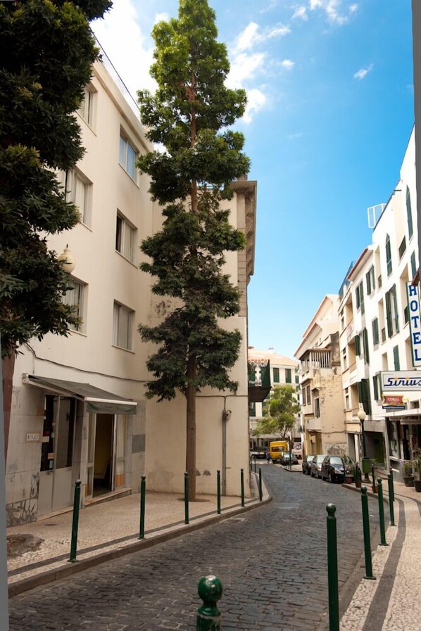 A cobblestone street lined with buildings, including a hotel with a sign that reads "HOTEL". - Residencial Monaco 38051-AL (Funchal)