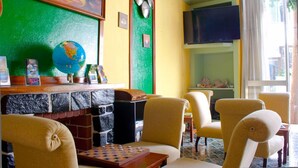 A room with a green and yellow wall, a globe, a chessboard, and a television. - Residencial Monaco 38051-AL (Funchal)