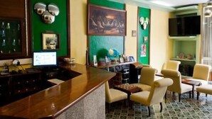 A hotel lobby with a wooden reception desk, several chairs, a television, and a painting on the wall. - Residencial Monaco 38051-AL (Funchal)