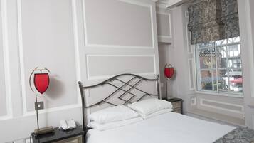 Een keurig opgemaakt slaapkamer met een bed, nachtkastjes en een raam met patroon gordijnen.