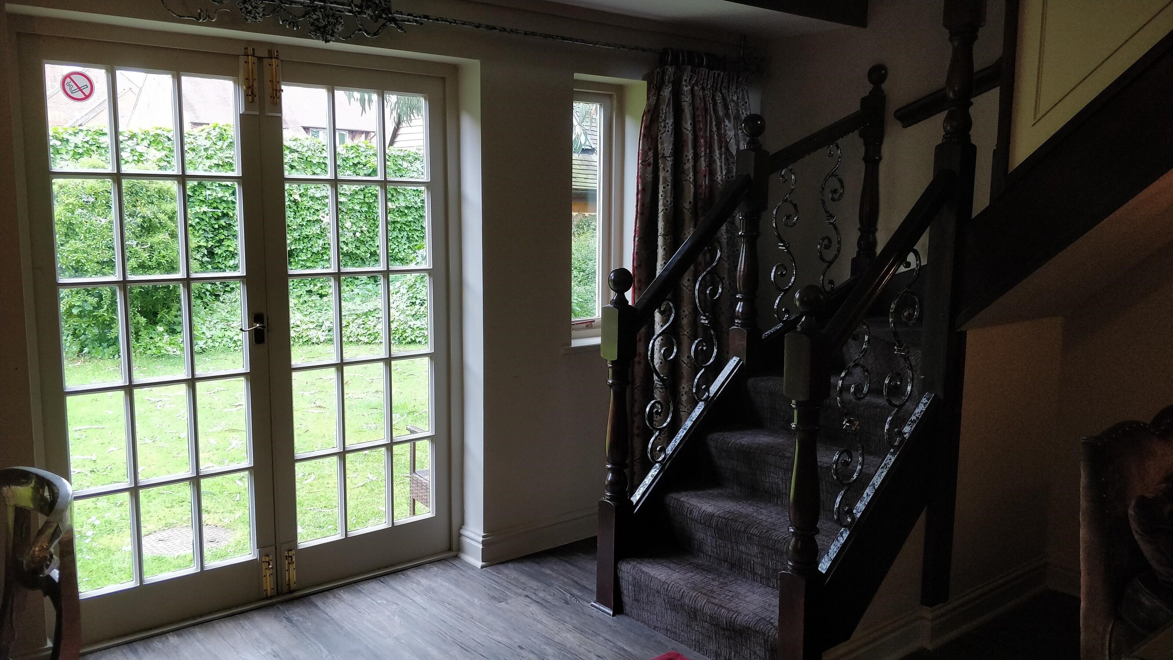 A staircase with ornate balusters and a view of a garden through large glass doors.