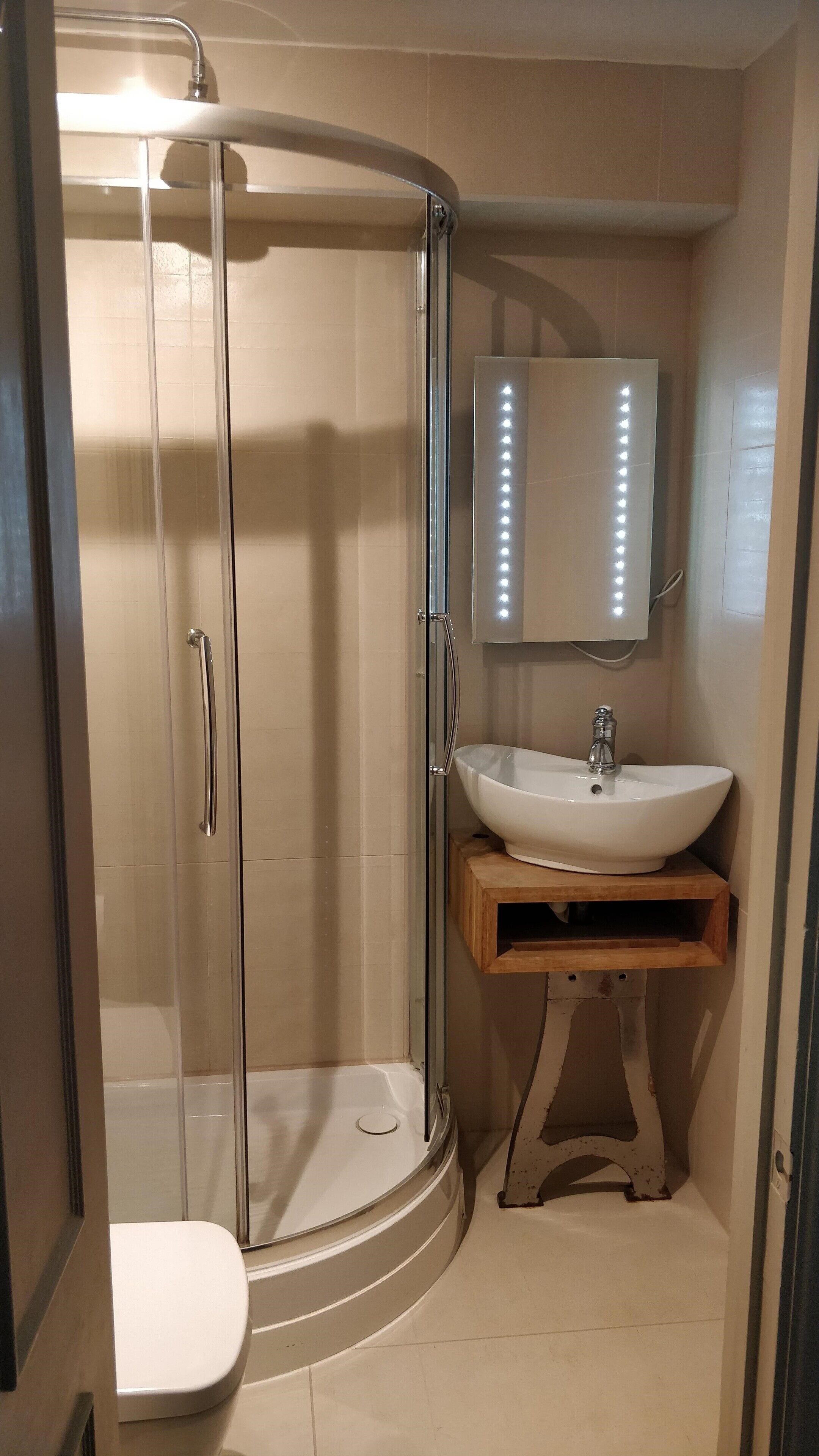 A bathroom with a glass-enclosed shower, a white sink, and a mirror above the sink.