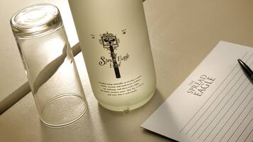 A bottle labeled "The Spread Eagle Hotel" with a candle beside it and a notepad with the hotel's name.