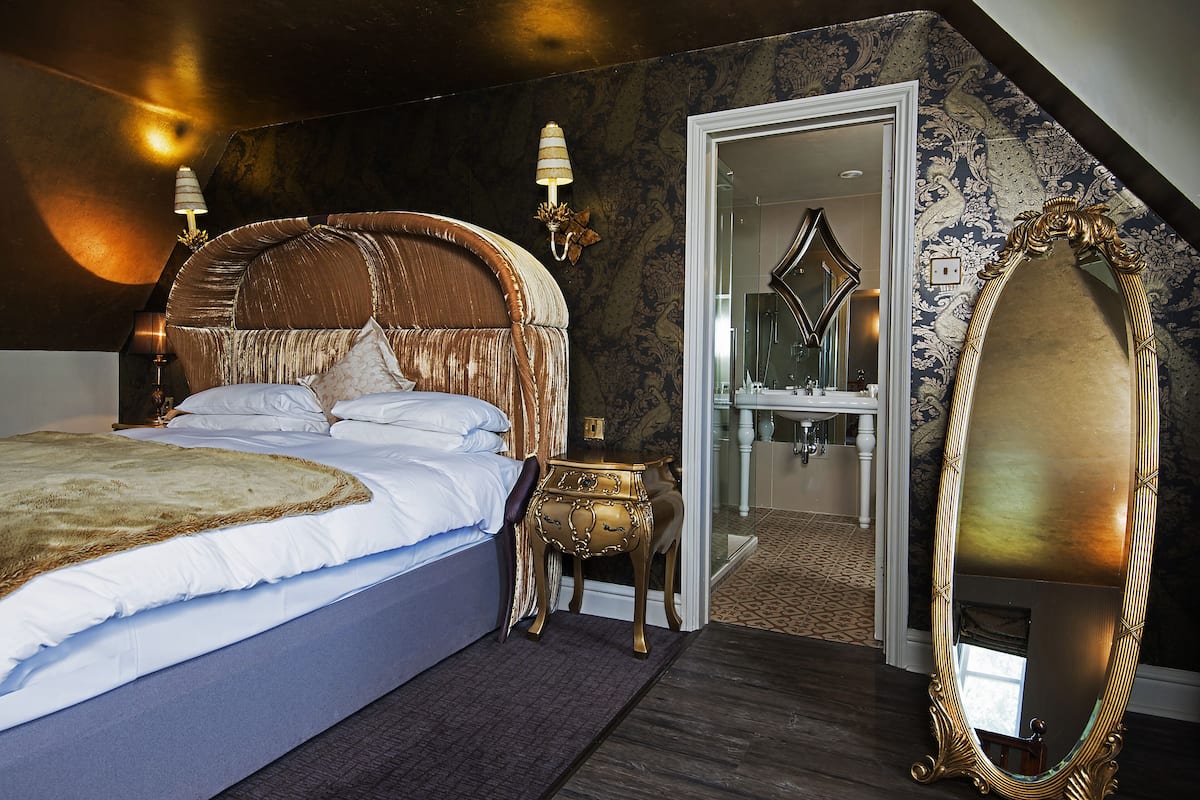 Un dormitorio con una cama grande, un espejo y una puerta que da a un baño.