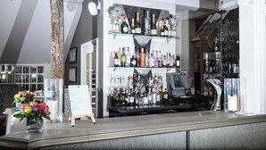 A bar area with shelves of liquor bottles, a cash register, and a flower vase. - The Spread Eagle Hotel (Thame)