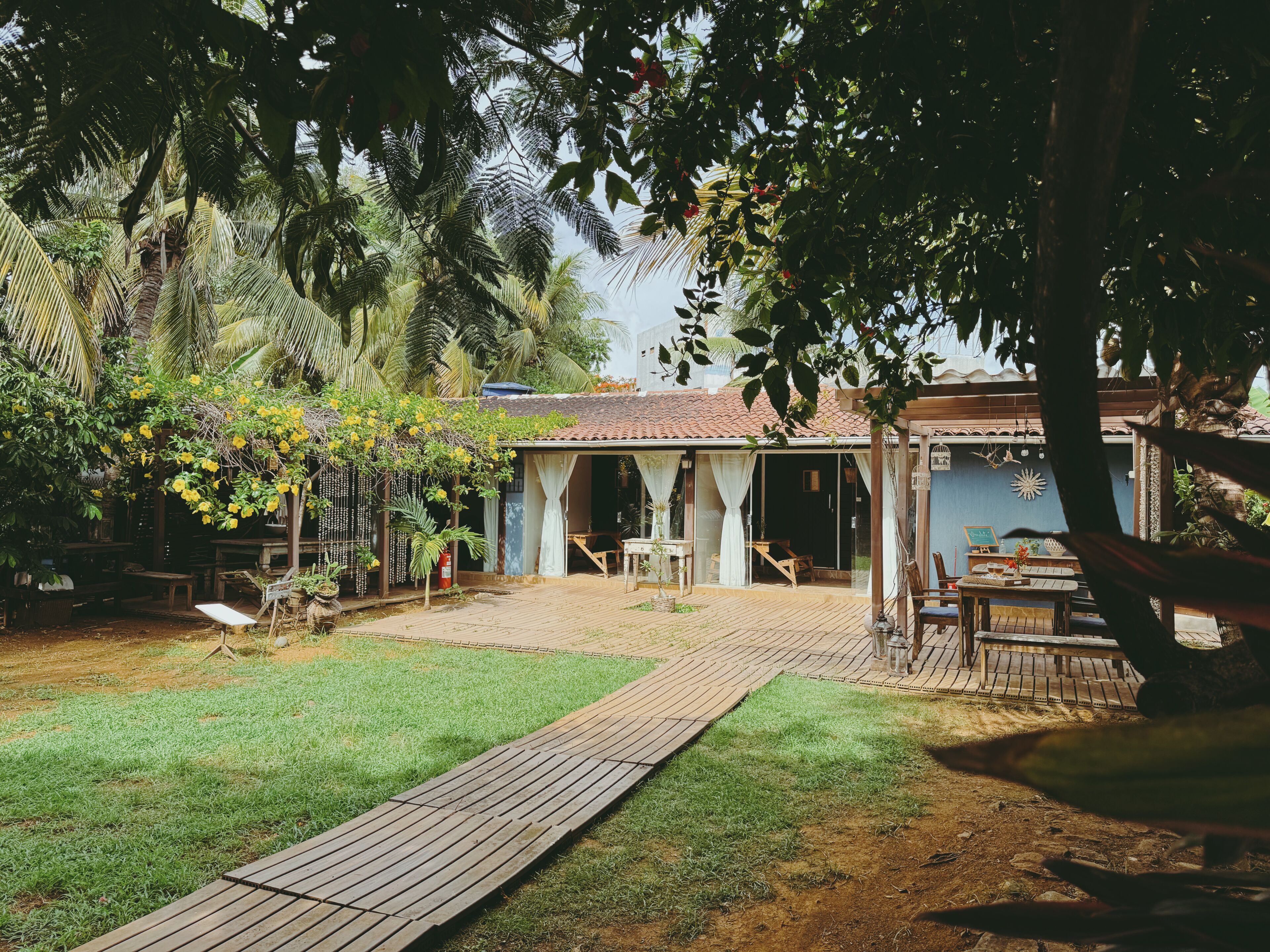 Une maison de style rustique dotée d’une terrasse en bois, d’un espace salon extérieur abrité et d’une végétation luxuriante.