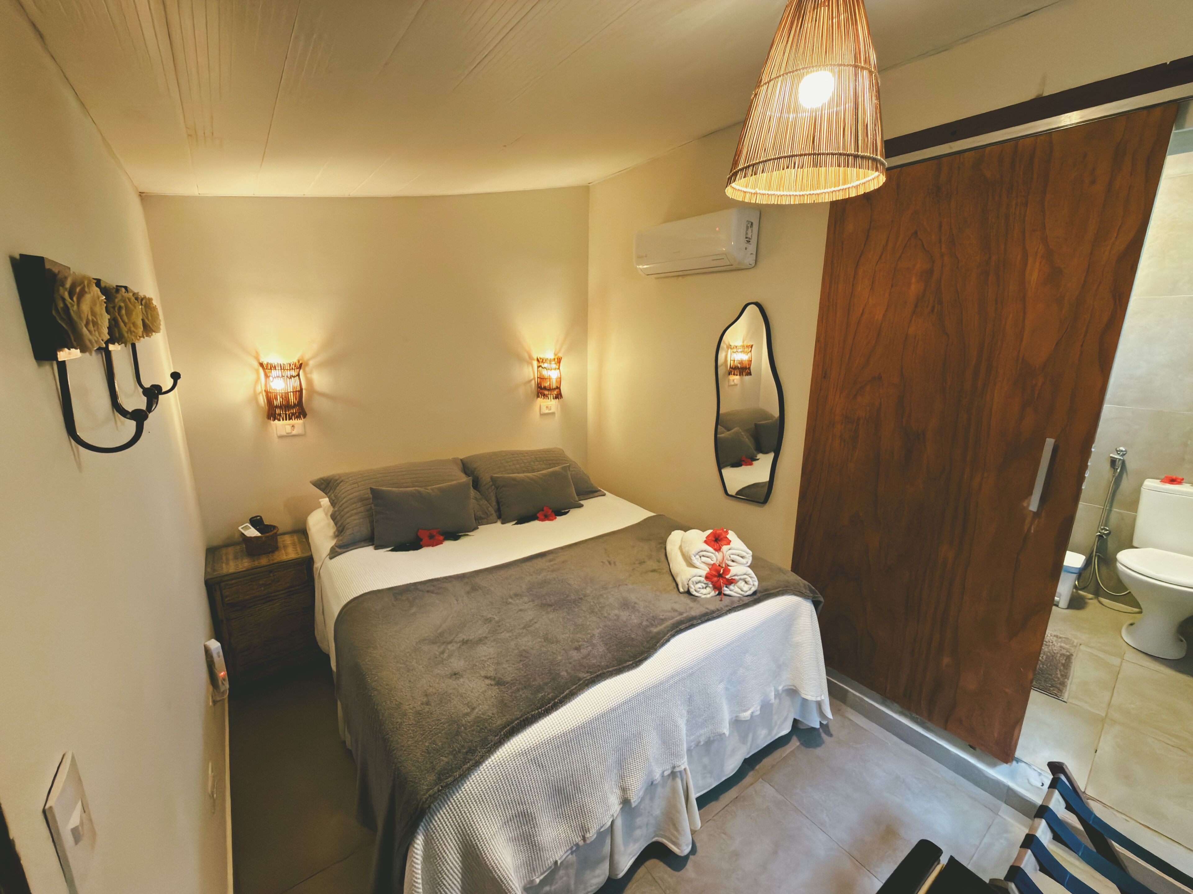 A bedroom with a bed, bedside lamps, a mirror, and a wooden door.