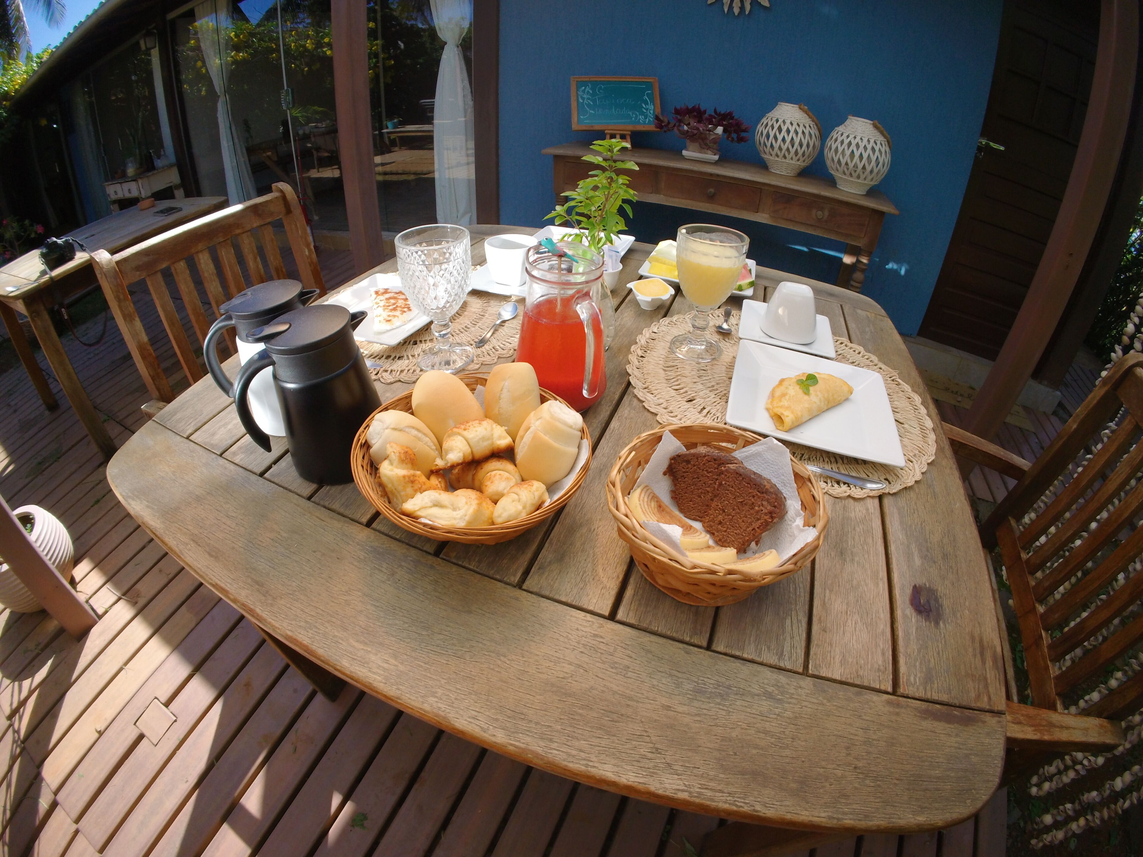 Ein Holztisch mit Frühstücksgebäck, darunter Brot, Gebäck und eine Korb mit Keksen.