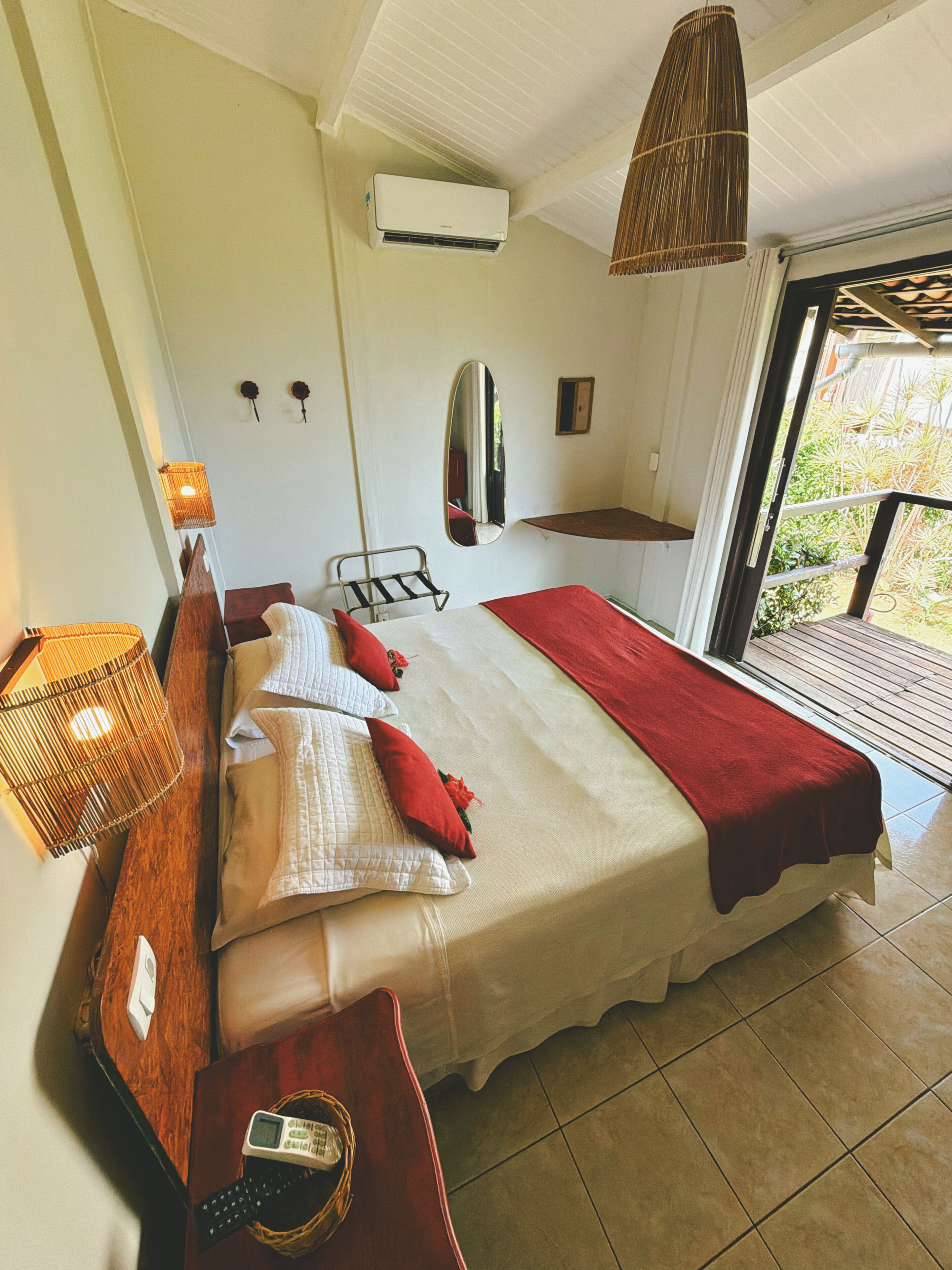 Een slaapkamer met een bed, nachtkastje, lamp, airconditioning en uitzicht op het buiten.