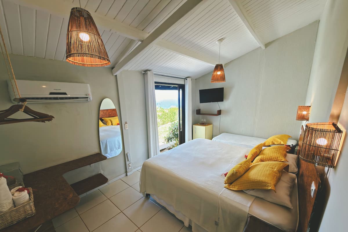 Quarto com cama, abajures, televisão, espelho e janela.
