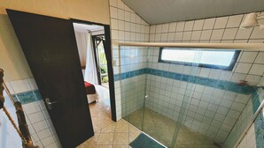 A bathroom with a shower, toilet, and a small window. - Pousada Ilha do Frade (Fernando de Noronha)