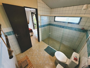 Un bagno con doccia, toilette e una piccola finestra.