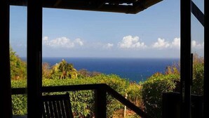 A covered outdoor area with a view of the ocean and a distant shoreline. - Pousada Ilha do Frade (Fernando de Noronha)
