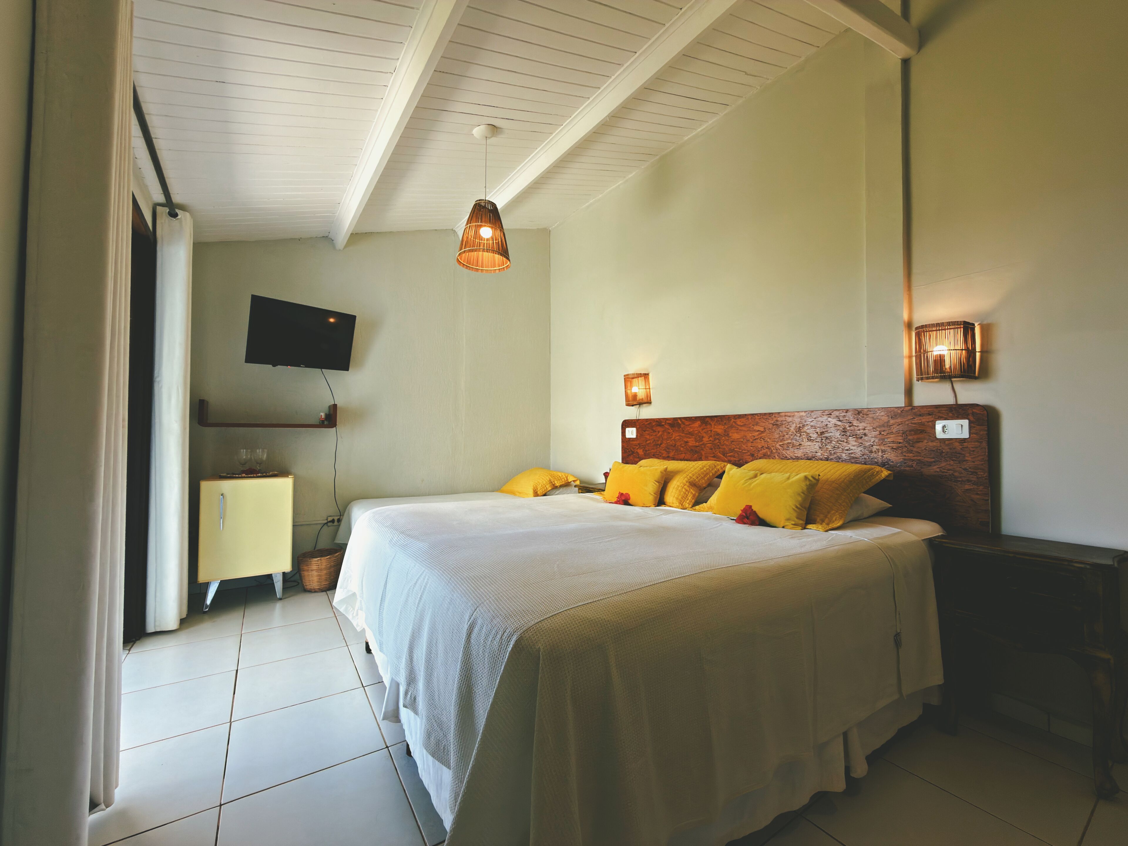 Une chambre à coucher comprenant un lit, un téléviseur et un luminaire fixé au mur.