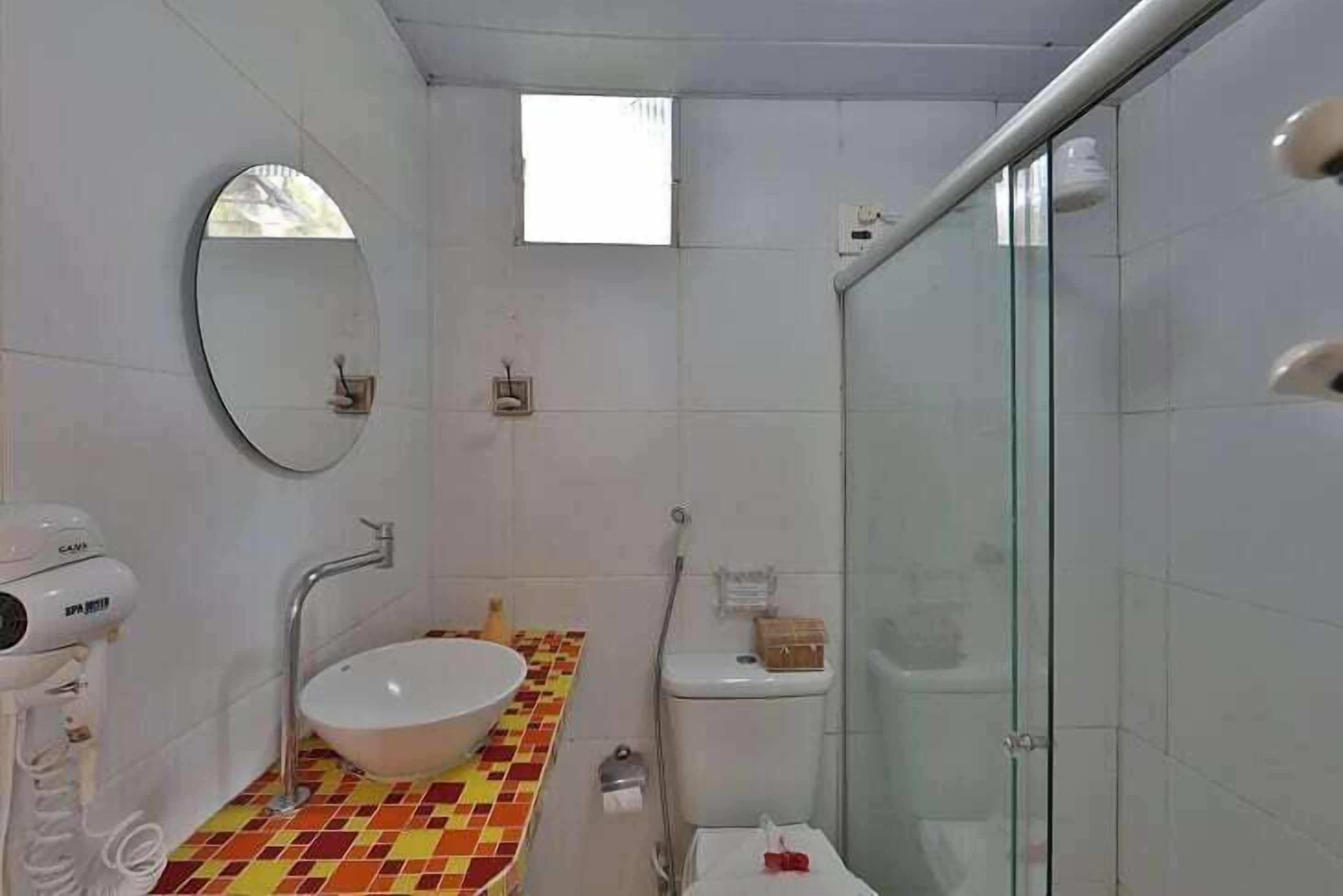 Ein Badezimmer mit weißem Waschbecken, einem Spiegel, einer Toilette und einer Duschkabine.