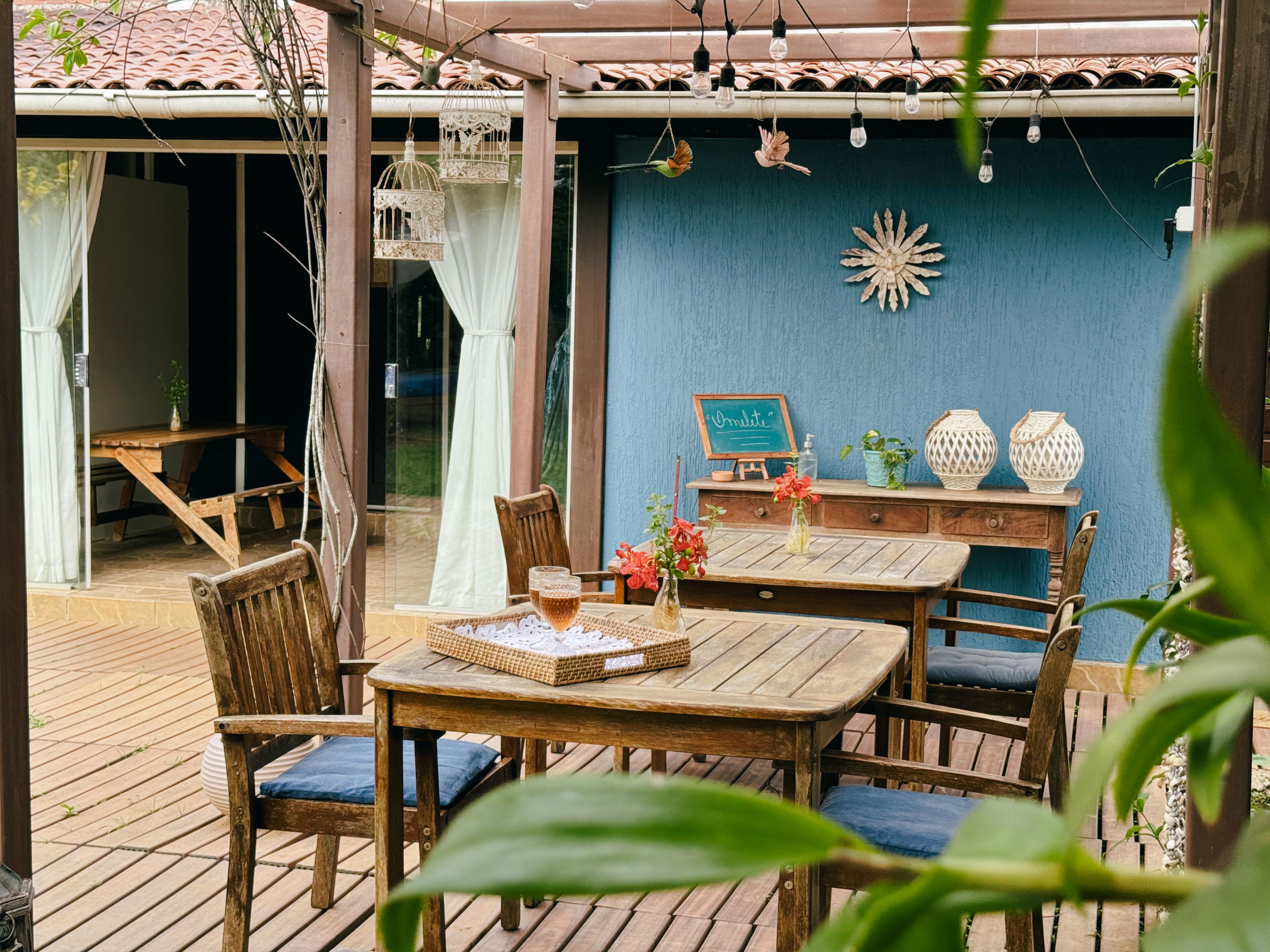A wooden deck with a table and chairs, a chalkboard sign, and decorative vases.