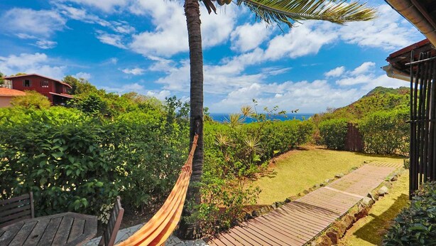 A hammock on a wooden deck, a wooden fence, and a view of the ocean. - Pousada Ilha do Frade (Fernando de Noronha)