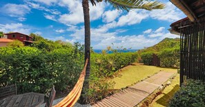 Un hamac sur une terrasse en bois, une clôture en bois et une vue sur l’océan.