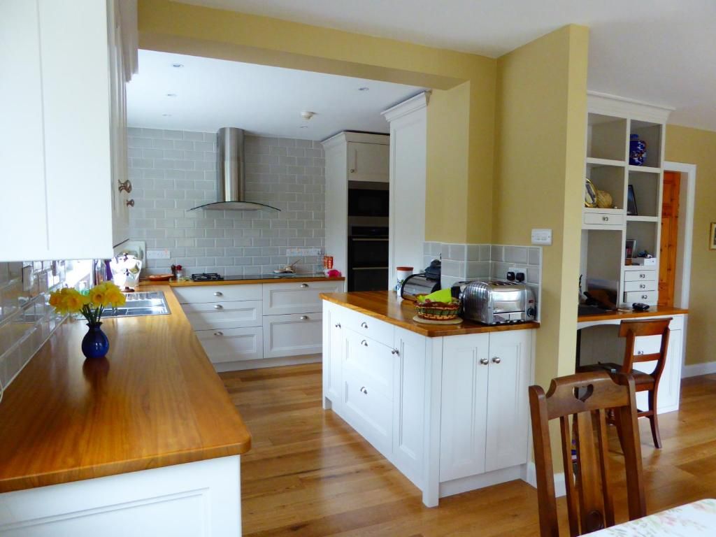 A kitchen with white cabinetry, a wooden countertop, and a built-in island with a toaster.