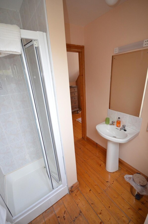 Un baño con ducha, lavamanos y espejo.