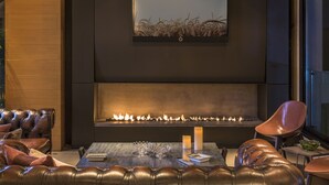 A modern living room with a fireplace, leather seating, and a coffee table with candles. - O Monot Hotel (Beirut)