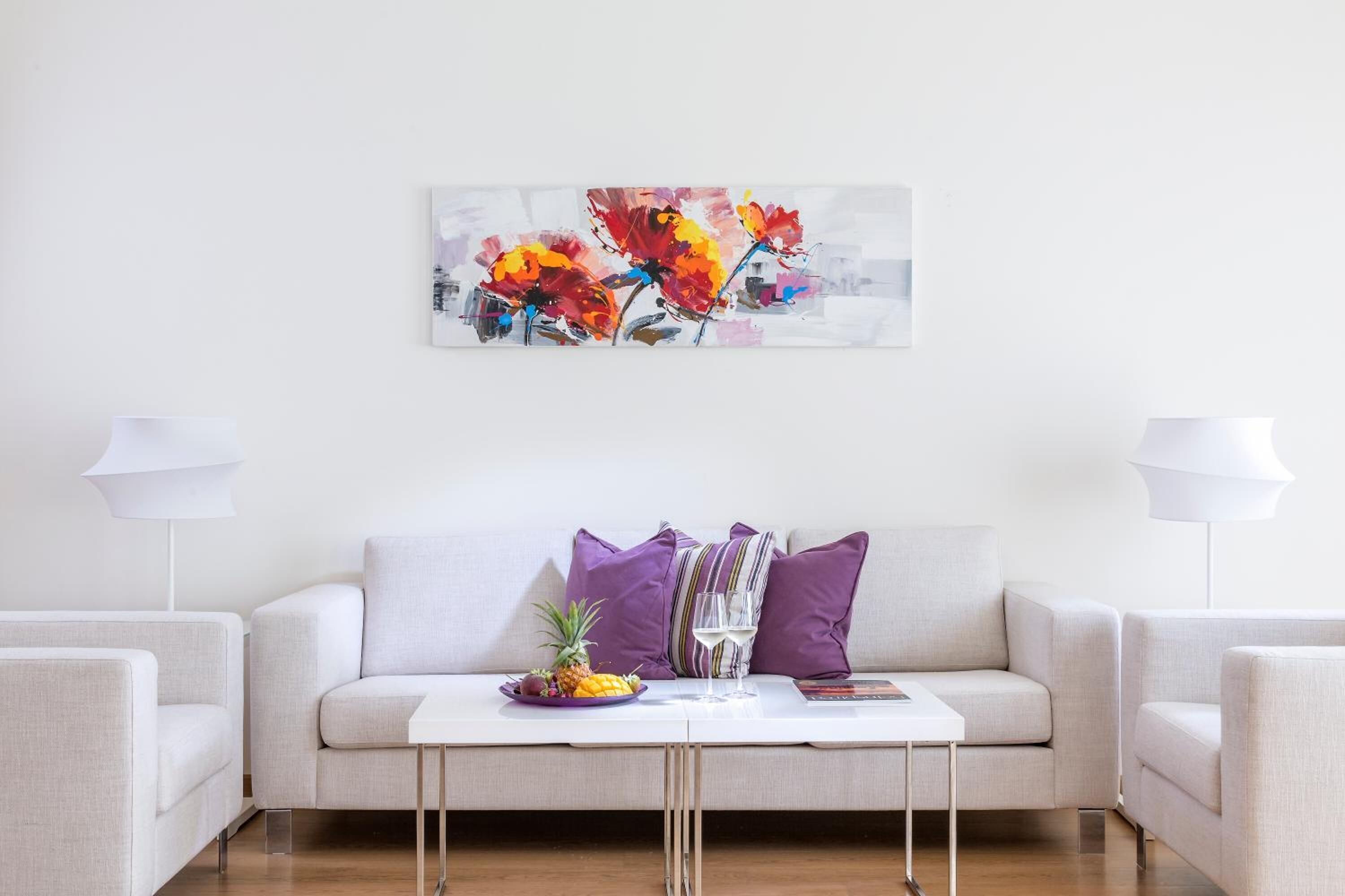 A modern living room with a sofa, two armchairs, a coffee table, and a painting.