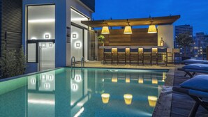 A swimming pool with a wooden deck and bar area. - O Monot Hotel (Beirut)
