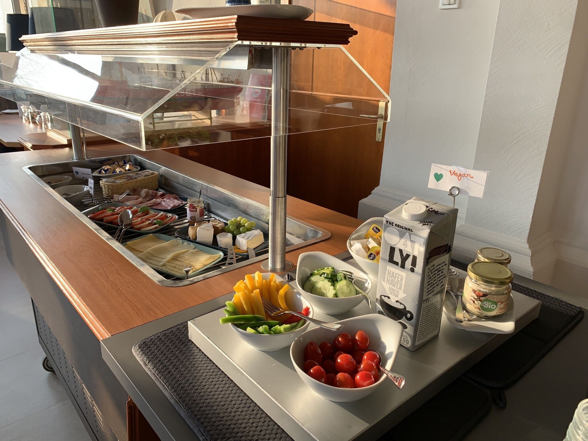 A buffet counter with various food items including cheese, fruits, and beverages.