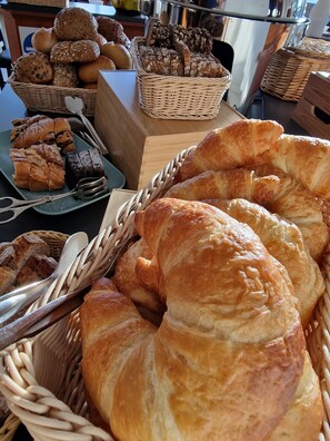 A variety of baked goods displayed in baskets and on a plate, including bread, rolls, and pastries. - Seehotel Neue Liebe (Cuxhaven)