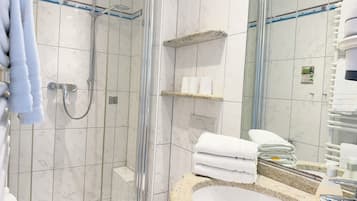 Ein modernes Badezimmer mit einer gläsernen Duschkabine, einem Waschbecken mit Granitplatte und einem Spiegel mit Handtuchhalter.