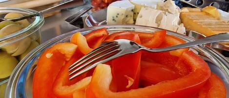 Una mesa de buffet con diversos alimentos, incluyendo pimientos rojos en rodajas, queso y otros platos preparados.