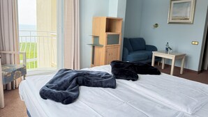 A hotel room with a bed, a desk, a chair, a wardrobe, and a view of the outdoors. - Seehotel Neue Liebe (Cuxhaven)