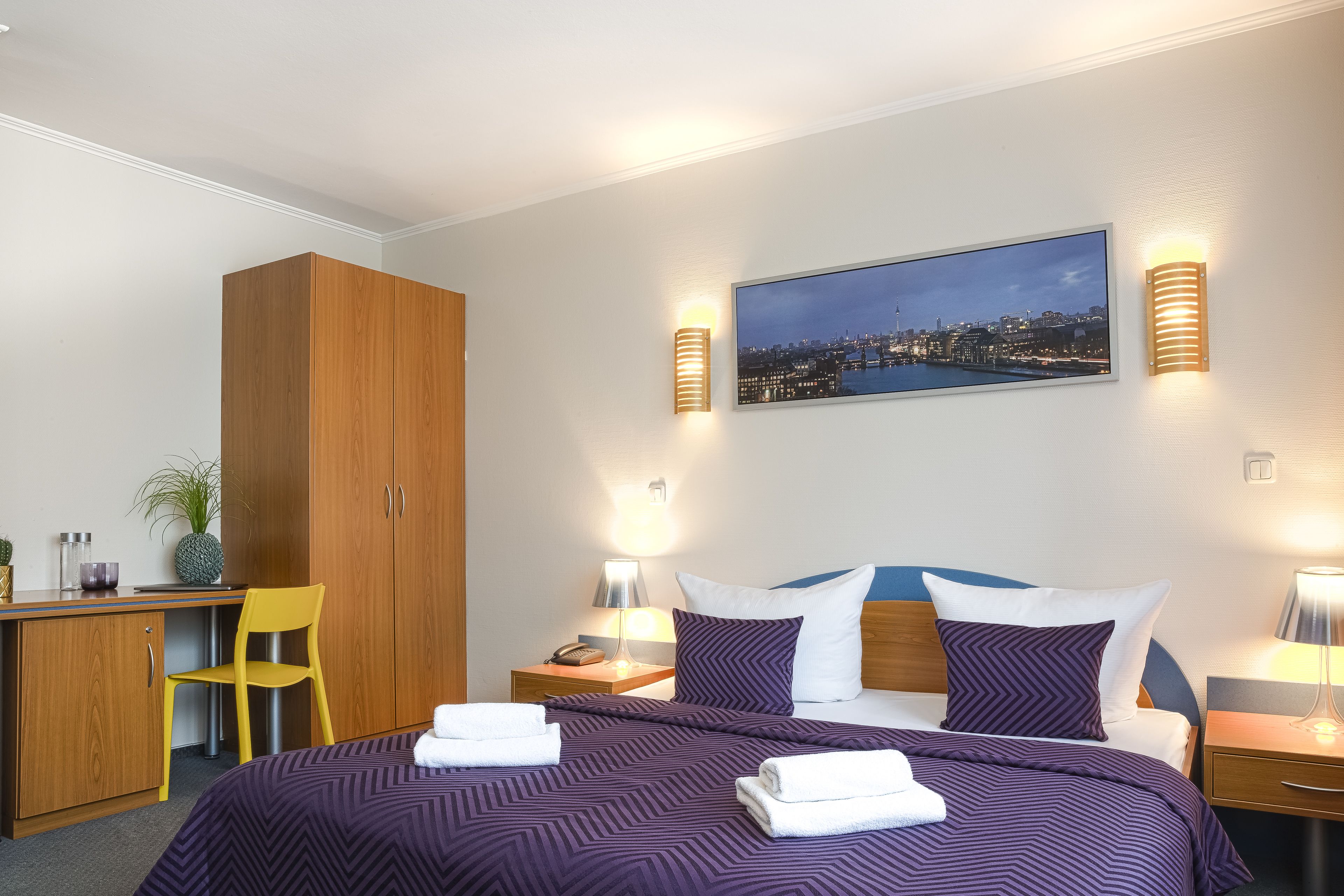 Une chambre d’hôtel comprenant un lit, un bureau, une chaise et une armoire.