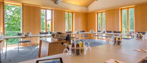 A conference room with large windows, wooden walls, and tables set up for a meeting.