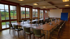 A conference room with long tables and chairs, large windows with a view of a baseball field, and a whiteboard. - Hotel Wo Der Hahn Kräht (Flein)