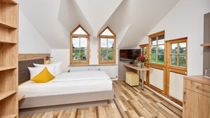 A modern bedroom with a loft-style design, featuring a bed, wooden shelving, and large windows with a view of greenery. - Hotel Wo Der Hahn Kräht (Flein)