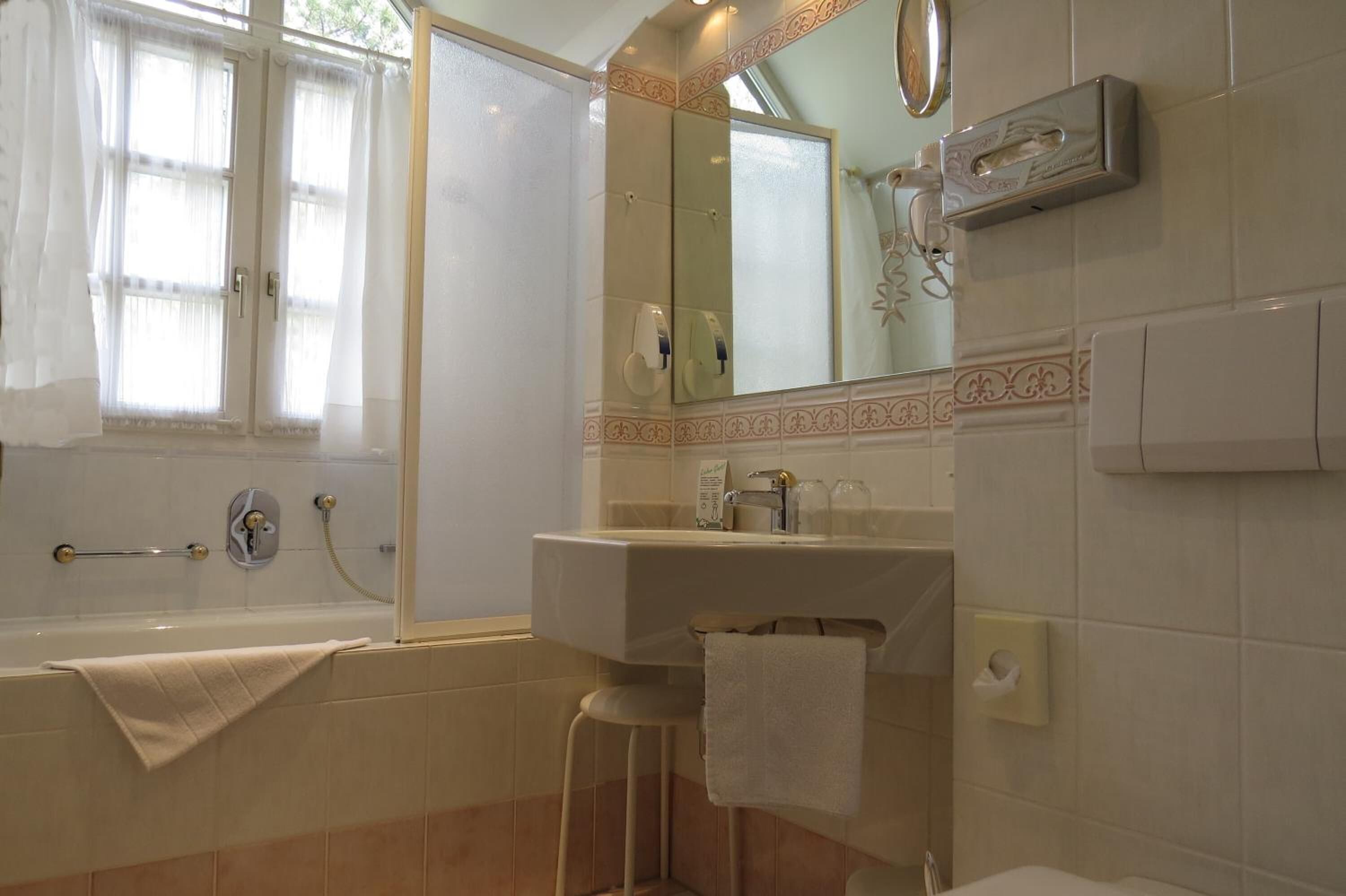 A bathroom with a bathtub, a sink, a mirror, and a towel rack.
