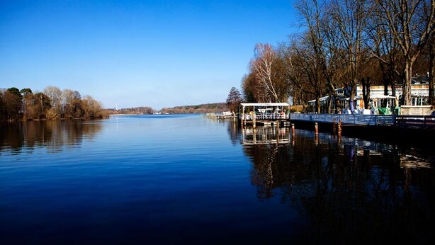 Un río tranquilo con un embarcadero y una zona de estar cubierta.