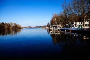 Un río tranquilo con un embarcadero y una zona de estar cubierta.