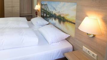 Habitación de hotel con una cama, dos lámparas de noche, un cuadro de un puente y un armario de madera.