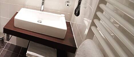 A bathroom with a white sink, a towel rack, and a towel on the floor.