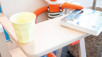 Una silla con un juguete de zorro tejido a crochet, una taza amarilla y un libro.