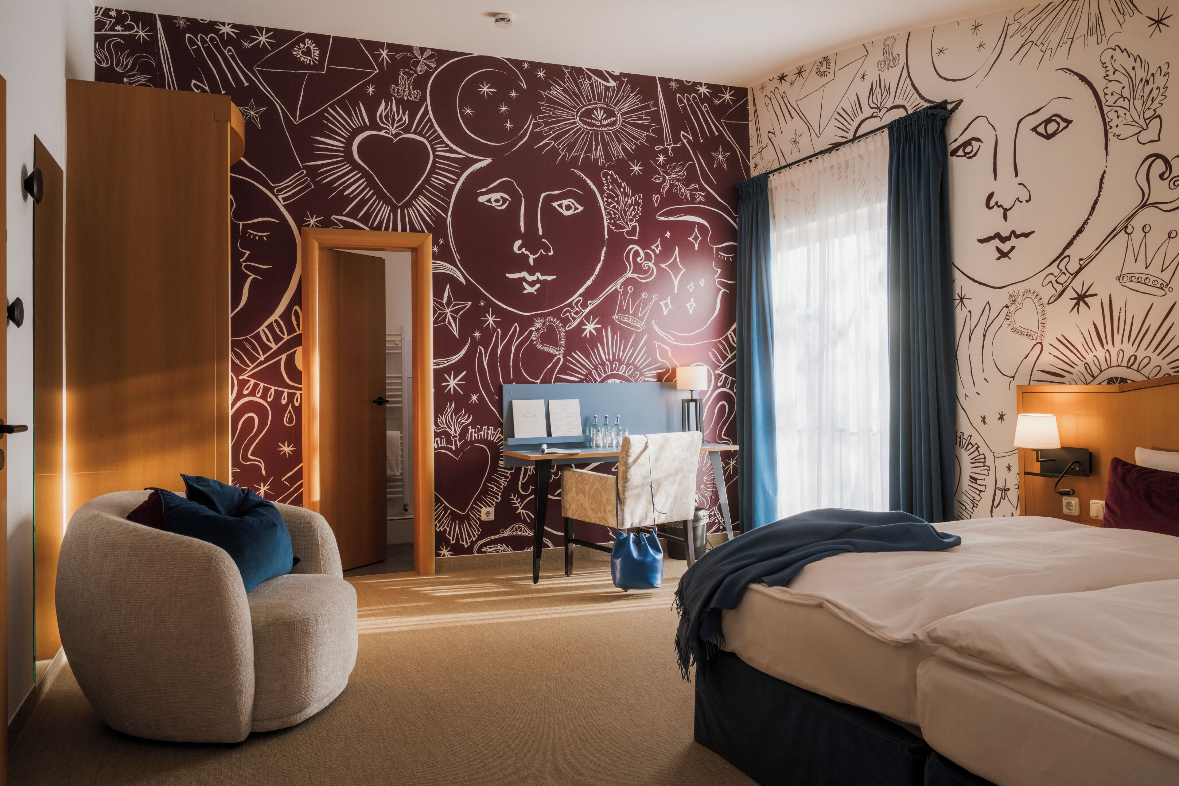 A hotel room with a bed, a desk, a chair, and a wardrobe.