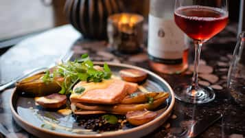 A plate of food with a glass of red wine on a table.