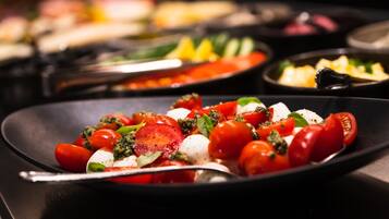 Primer plano de un plato con tomates, mozzarella y albahaca sobre una fuente negra.