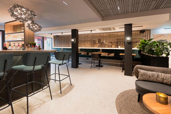 Un área de bar moderna con taburetes, un sofá y una mesa redonda de madera.