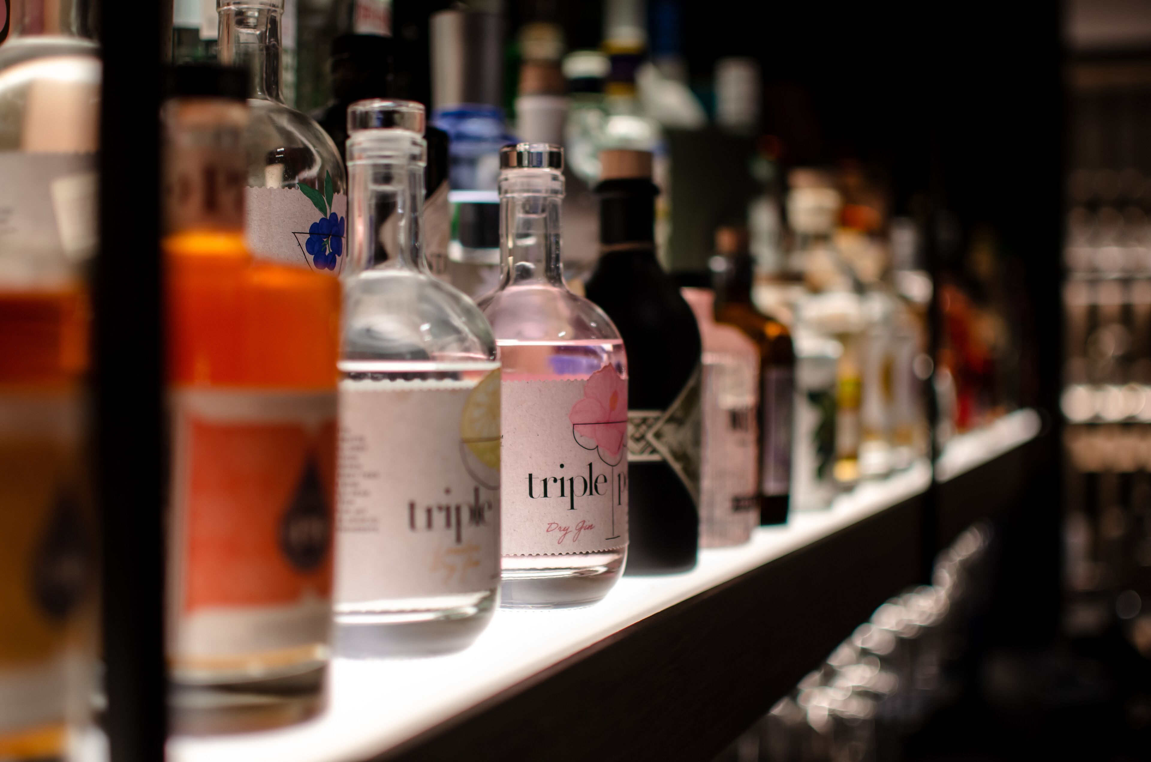 A bar shelf with various bottles of alcohol, including a prominently labeled bottle of Triple P.