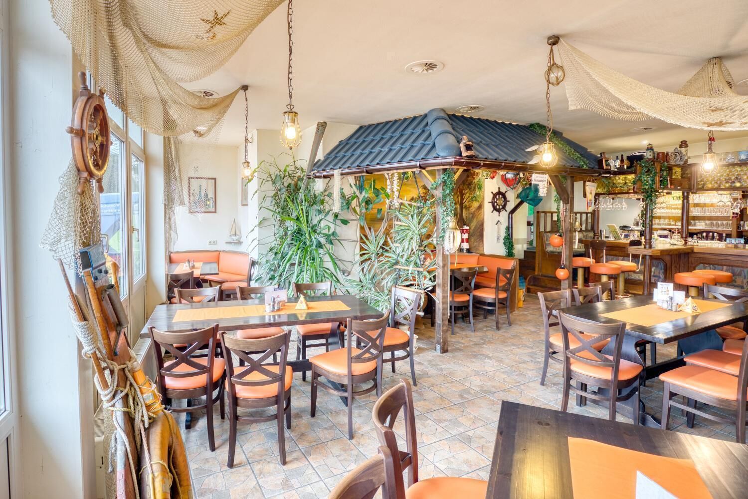 Un restaurant doté de nombreuses tables et chaises, d’un bar et d’une décoration sur le thème de la marine.