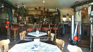 Un espace bar avec des meubles en bois, une table centrale et des tabourets rouges.