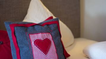 A close-up of a pillow with a heart patch and red trim on a bed.